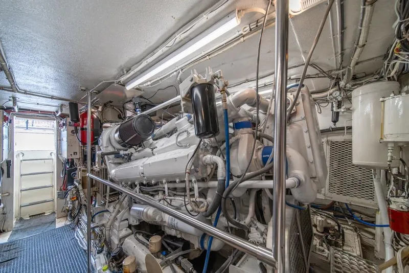Slide: The Image of Engine room of 1988 Hatteras 65 Sportfish yacht, showcasing complex machinery and piping. - 49