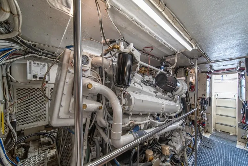 Slide: The Image of Engine room of 1988 Hatteras 65 Sportfish, showcasing complex machinery and wiring. - 50