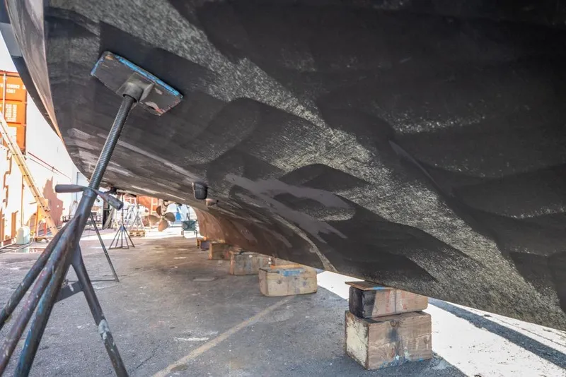 Slide: The Image of 1988 Hatteras 65 Sportfish boat hull on dry dock, supported by stands and blocks. - 54