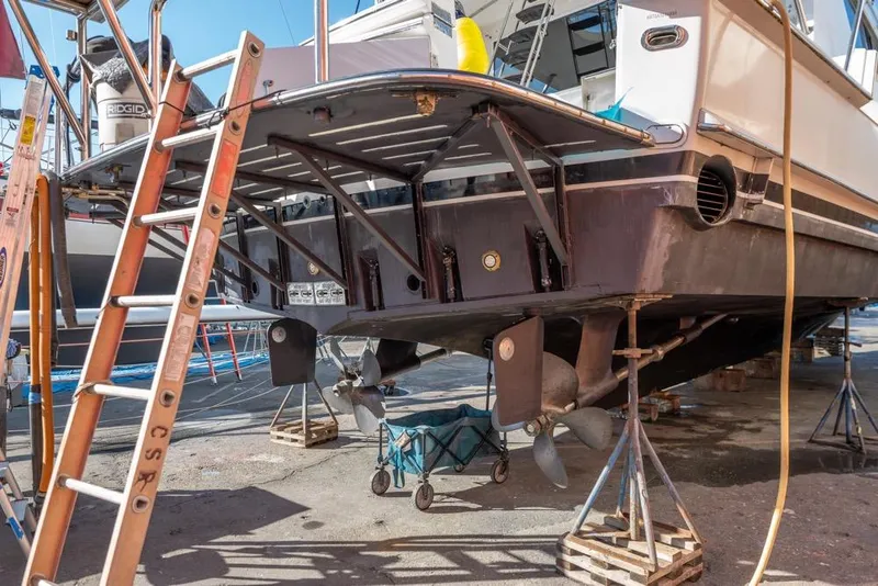 Slide: The Image of 1988 Hatteras 65 Sportfish boat under maintenance, showing propellers and hull structure. - 68