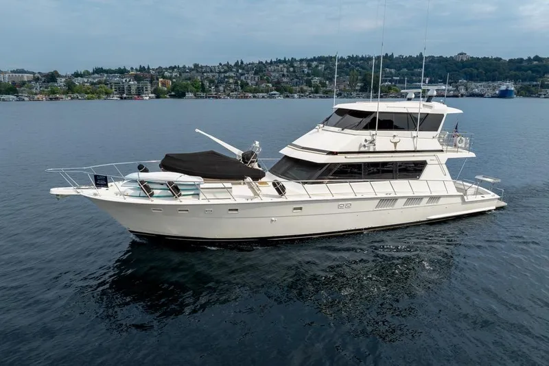 Slide: The Image of 1988 Hatteras 65 Sportfish yacht on calm water with cityscape background. - 7