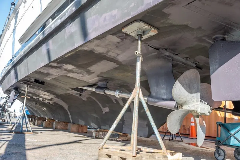 Slide: The Image of 1988 Hatteras 65 Sportfish boat under maintenance, showing propeller and hull details. - 78
