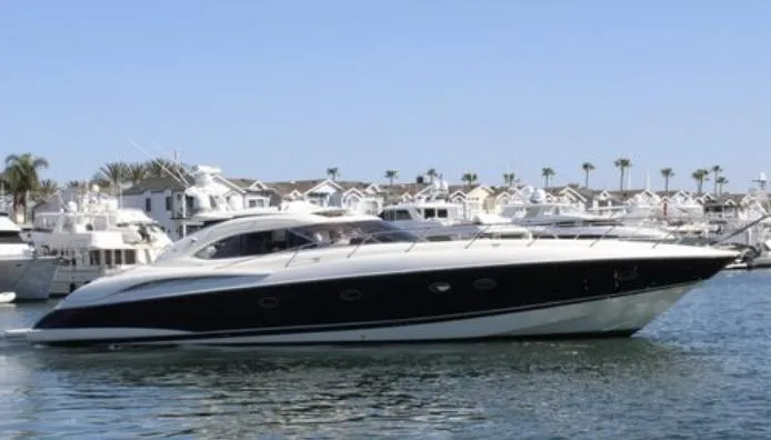 Slide: The Image of Sunseeker Predator 60 yacht, 2000 model, cruising in a marina with palm trees. - 2
