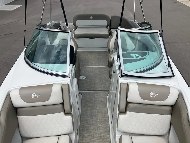 Slide: The Image of 2023 Crownline Eclipse E235 boat interior with beige and white seating, open windshield, and carpeted floor. - 16