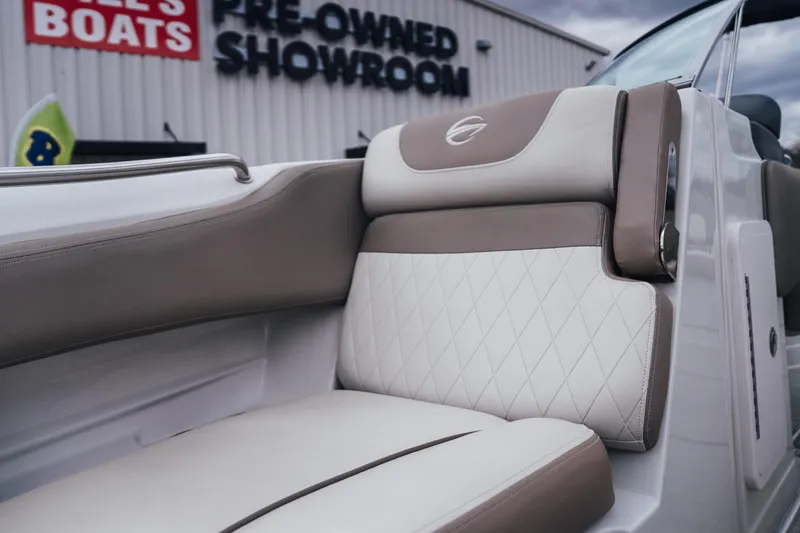 Slide: The Image of 2023 Crownline Eclipse E235 boat interior with beige and white seating at a showroom. - 27