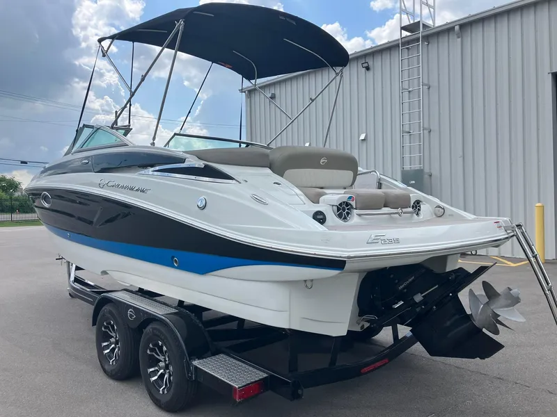Slide: The Image of 2023 Crownline Eclipse E235 boat on trailer, featuring sleek design and bimini top. - 3