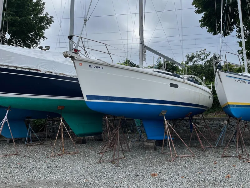 The Image of 1995 Hunter 336 sailboat on stands, white hull with blue bottom, overcast sky. - 1