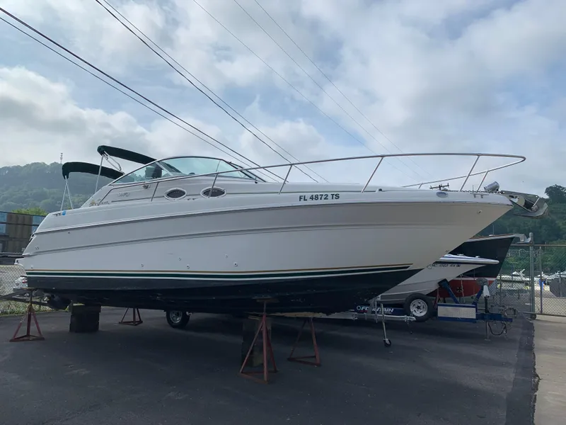 Slide: The Image of 2000 Sea Ray 270 Sundancer boat on stands, outdoors, under cloudy sky. - 1