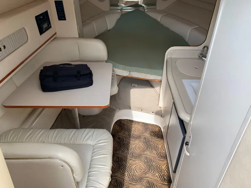 Slide: The Image of Interior of 2000 Sea Ray 270 Sundancer boat with seating, table, and compact kitchenette. - 10