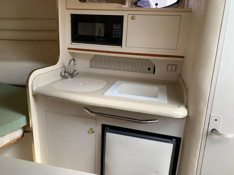 Slide: The Image of 2000 Sea Ray 270 Sundancer cabin kitchenette with sink, microwave, and storage. - 12
