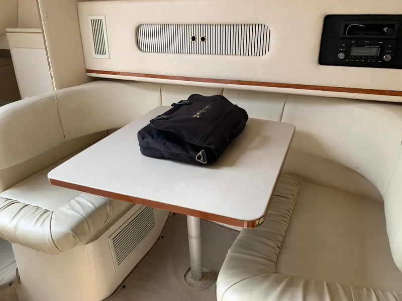 Slide: The Image of Interior of 2000 Sea Ray 270 Sundancer with table, seating, and a black bag. - 14