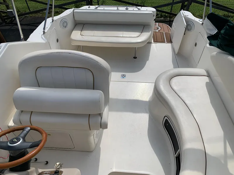 Slide: The Image of 2000 Sea Ray 270 Sundancer boat interior with white seating and wooden steering wheel. - 3