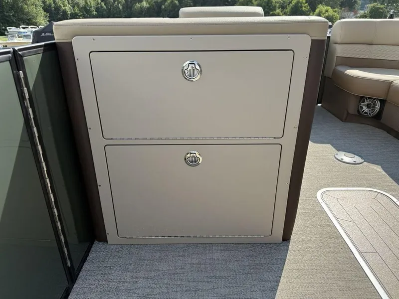 Slide: The Image of 2025 Godfrey Monaco 235 SFL boat interior storage compartment with beige upholstery and carpeted flooring. - 17
