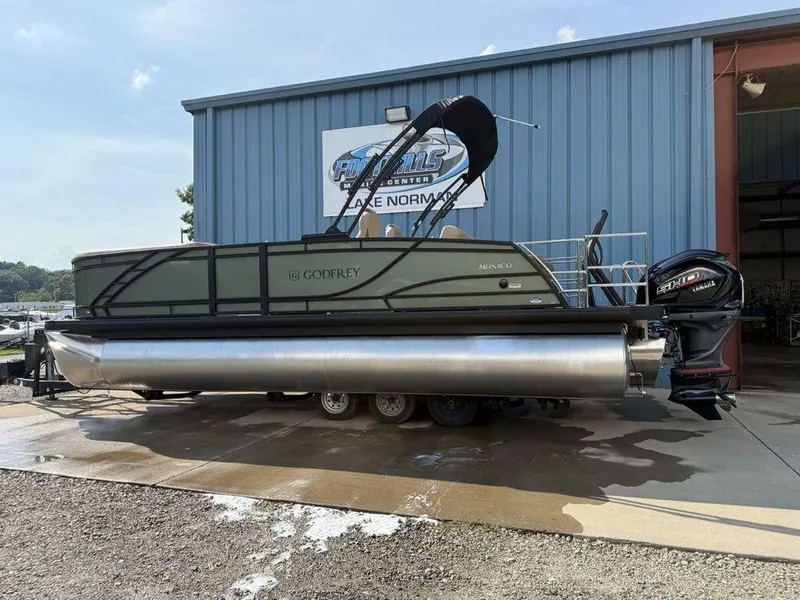Slide: The Image of 2025 Godfrey Monaco 235 SFL iMPACT pontoon boat with Yamaha engine, parked outside a marina. - 4
