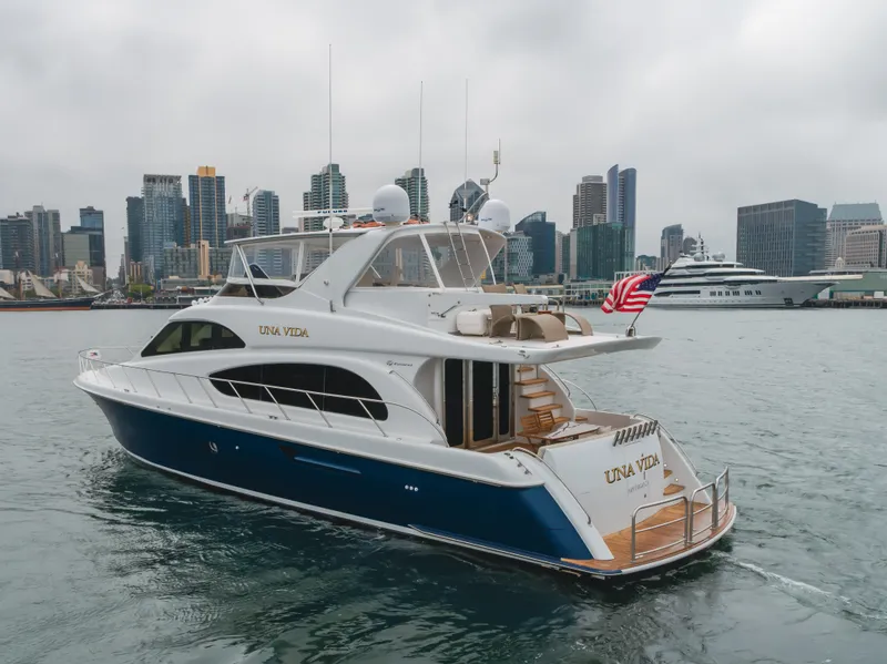 Slide: The Image of 2007 Hatteras 64 Motor Yacht in harbor, city skyline background, American flag displayed. - 3