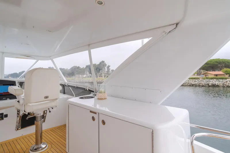 Slide: The Image of 2007 Hatteras 64 Motor Yacht helm with white seating and coastal view. - 34