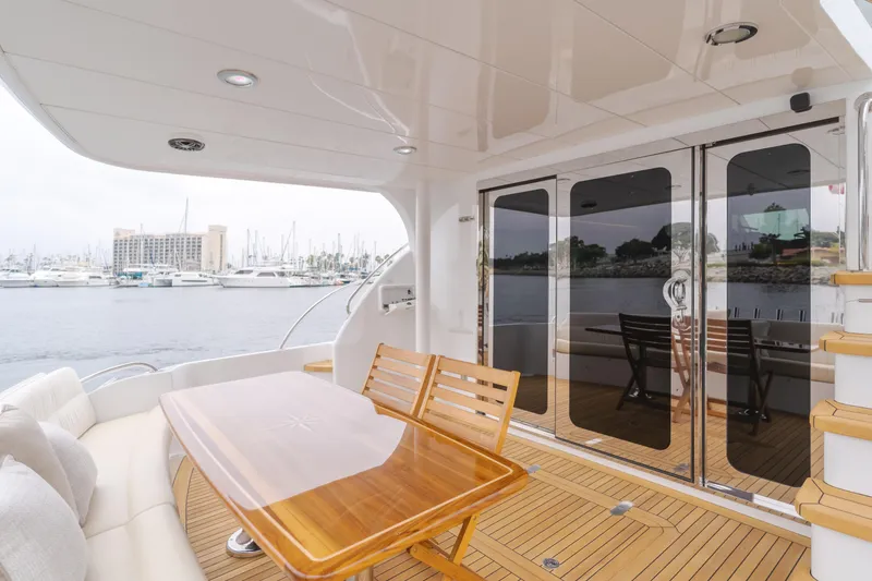 Slide: The Image of Luxurious 2007 Hatteras 64 Motor Yacht deck with wooden table and marina view. - 39