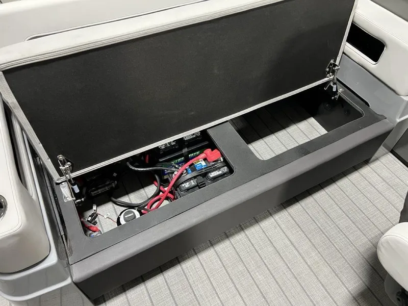 Slide: The Image of Open storage compartment in 2025 Godfrey AquaPatio 235 SFLC boat, revealing electrical components. - 25