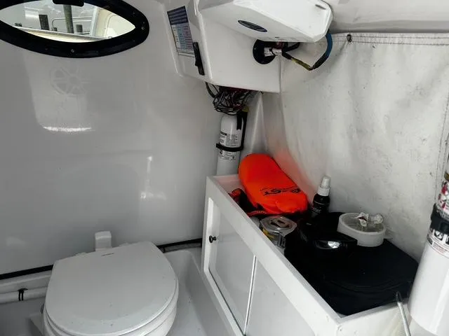 Slide: The Image of Interior of 2018 Sportsman Open 252 Center Console boat with toilet and storage area. - 13