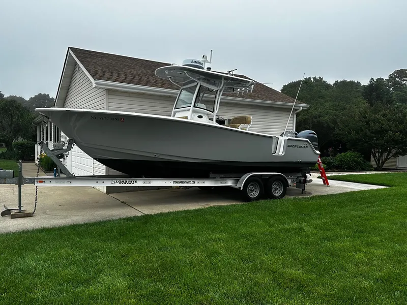 Slide: The Image of 2018 Sportsman Open 252 Center Console boat on trailer in residential driveway. - 2