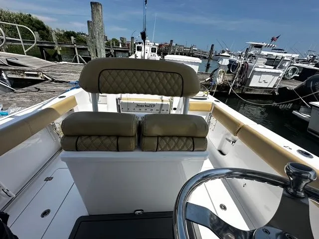 Slide: The Image of 2018 Sportsman Open 252 Center Console boat at marina, featuring tan seating and steering wheel. - 27