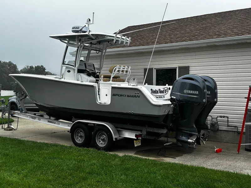 Slide: The Image of 2018 Sportsman Open 252 Center Console boat on trailer, parked beside a house. - 3