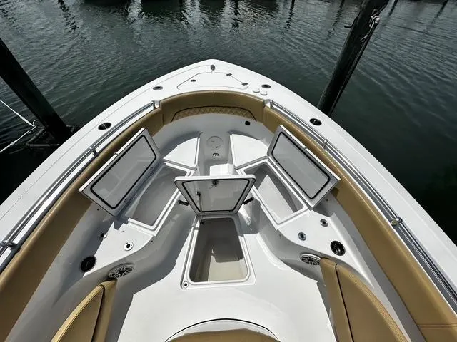 Slide: The Image of 2018 Sportsman Open 252 Center Console boat with open storage compartments, docked on calm water. - 5