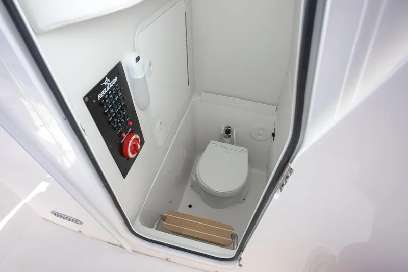 Slide: The Image of Interior of 2026 Regulator 23 boat showing compact marine toilet and control panel. - 22