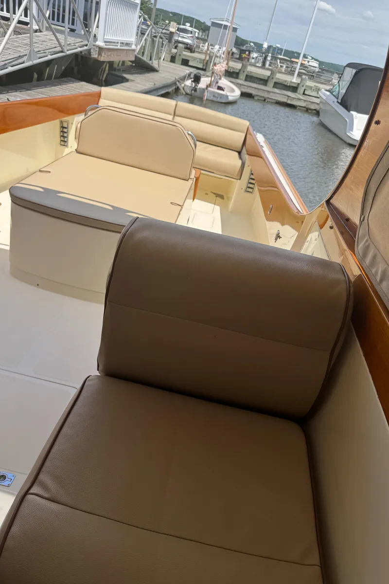 Slide: The Image of 1999 Hinckley Picnic boat interior with beige seating at a marina. - 11