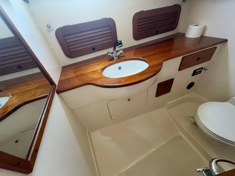 Slide: The Image of Hinckley Picnic 1999 boat bathroom with wooden countertop, sink, and toilet. - 14
