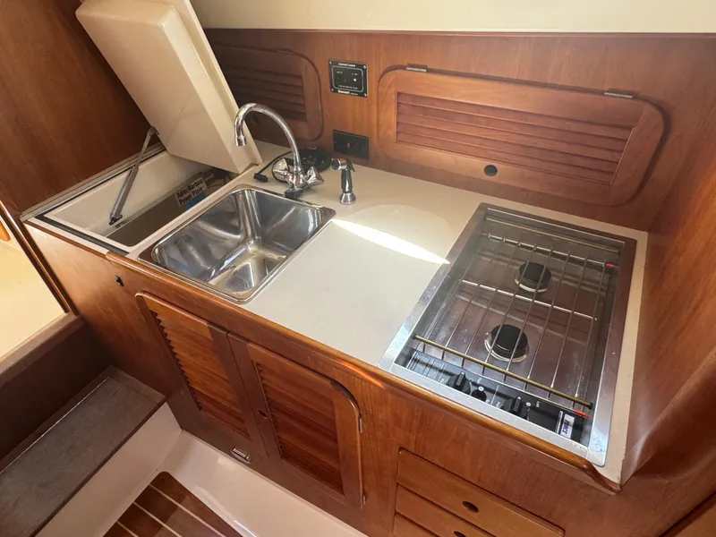 Slide: The Image of 1999 Hinckley Picnic yacht kitchen with sink, stove, and wooden cabinetry. - 22