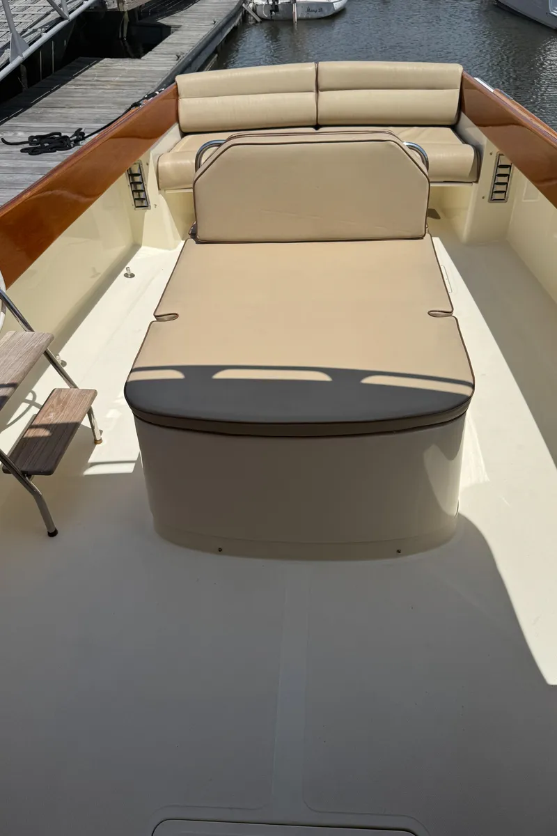 Slide: The Image of 1999 Hinckley Picnic boat interior with beige seating and wooden accents, docked by the water. - 9