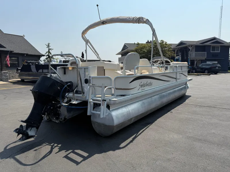 Slide: The Image of 2006 Sweetwater 23860DF pontoon boat parked on pavement near buildings. - 4