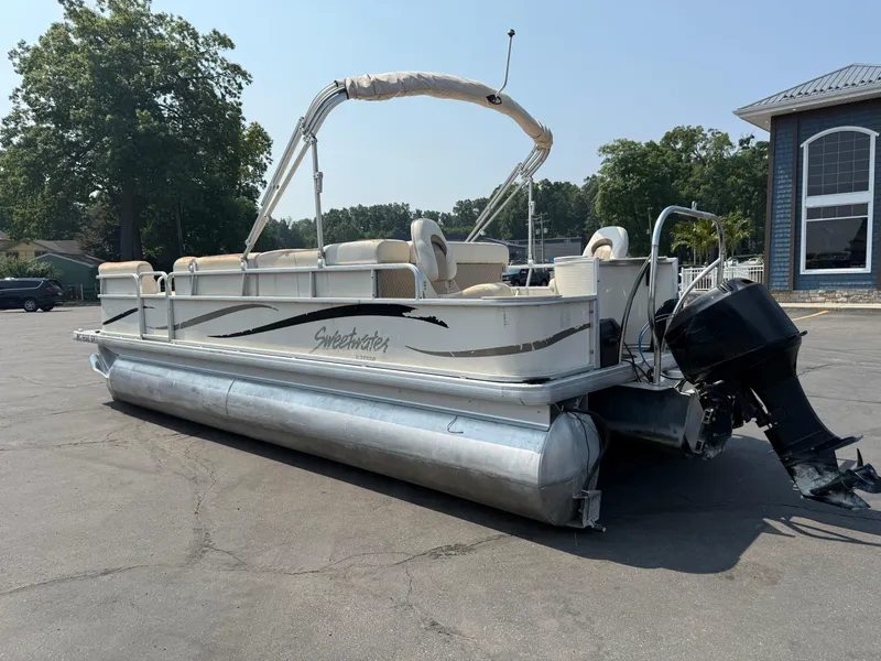 Slide: The Image of 2006 Sweetwater 23860DF pontoon boat parked outdoors, featuring a canopy and outboard motor. - 5