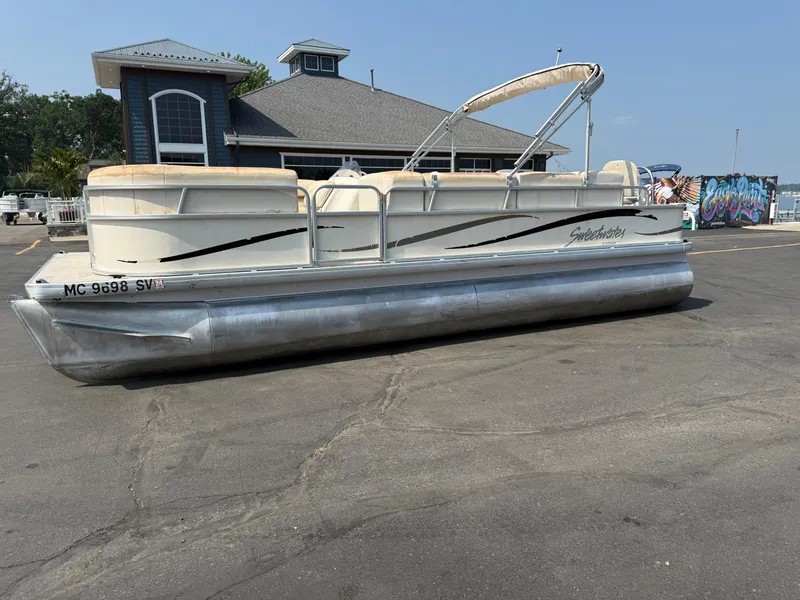 Slide: The Image of 2006 Sweetwater 23860DF pontoon boat parked near a marina building. - 6