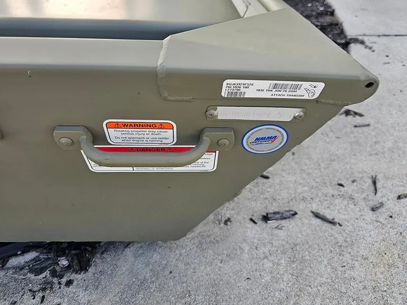 Slide: The Image of 2026 Tracker Grizzly 1036 Utility boat corner with warning labels and handle. - 5