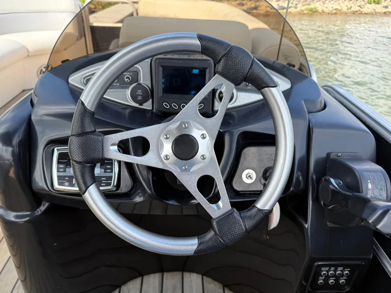 Slide: The Image of Steering wheel of a 2000 Sanpan 25 boat, featuring a modern dashboard and controls. - 10