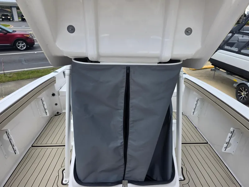 Slide: The Image of 2025 Yamaha Boats 195 FSH Sport interior with storage compartment and gray cover. - 11