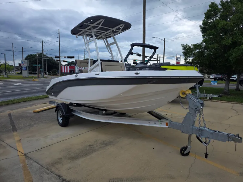 Slide: The Image of 2025 Yamaha Boats 195 FSH Sport on trailer in parking lot, overcast sky. - 2