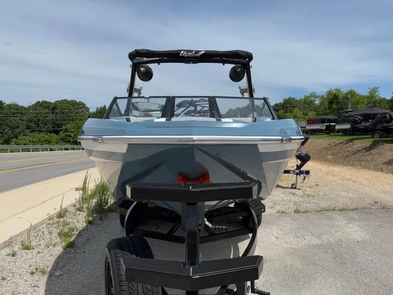 Slide: The Image of 2022 Tigé 21ZX boat on trailer, parked roadside under clear sky. - 2