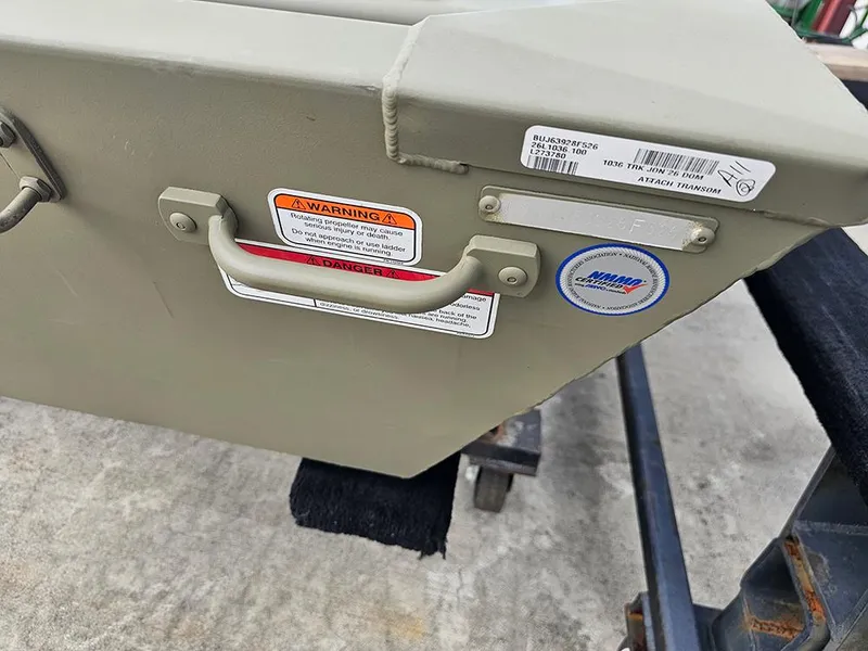 Slide: The Image of 2026 Tracker Grizzly 1036 Utility boat transom with warning labels and certification sticker. - 3