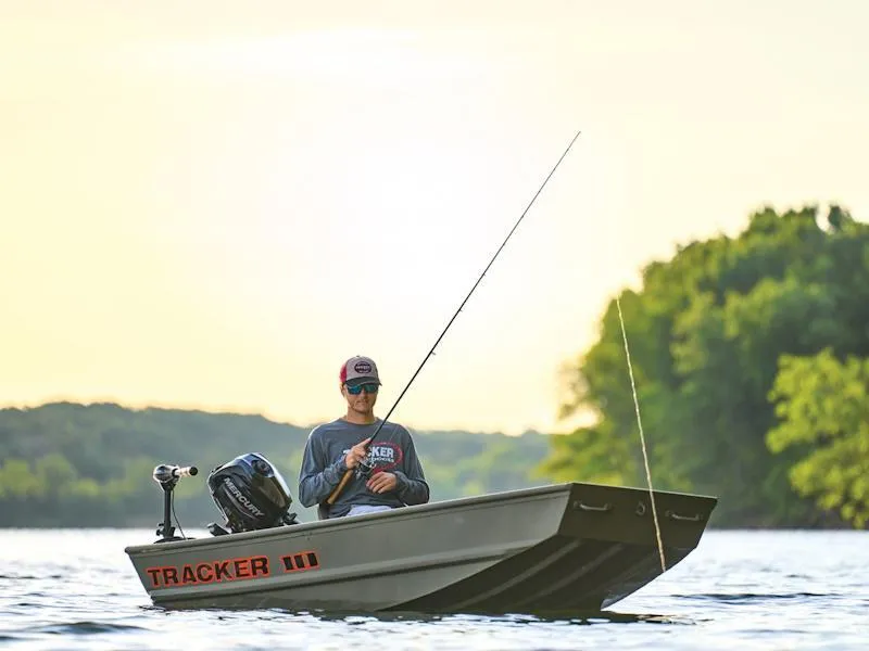 Slide: The Image of Man fishing on 2026 Tracker Grizzly 1036 Utility boat in serene lake setting. - 4