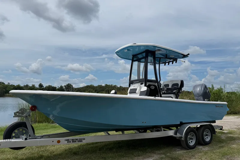 The Image of 2026 Tidewater 2300 Carolina Bay boat on trailer by a lake under cloudy sky. - 0