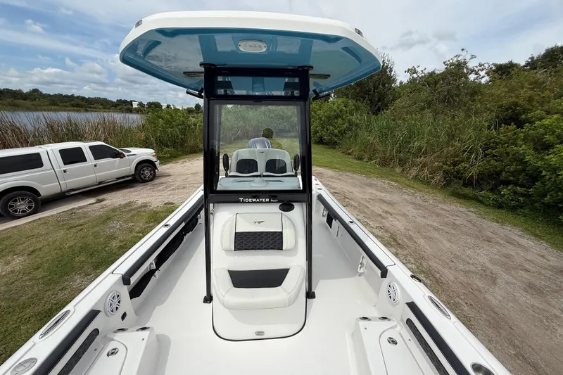 Slide: The Image of 2026 Tidewater 2300 Carolina Bay boat with T-top, parked near a lake and truck. - 20