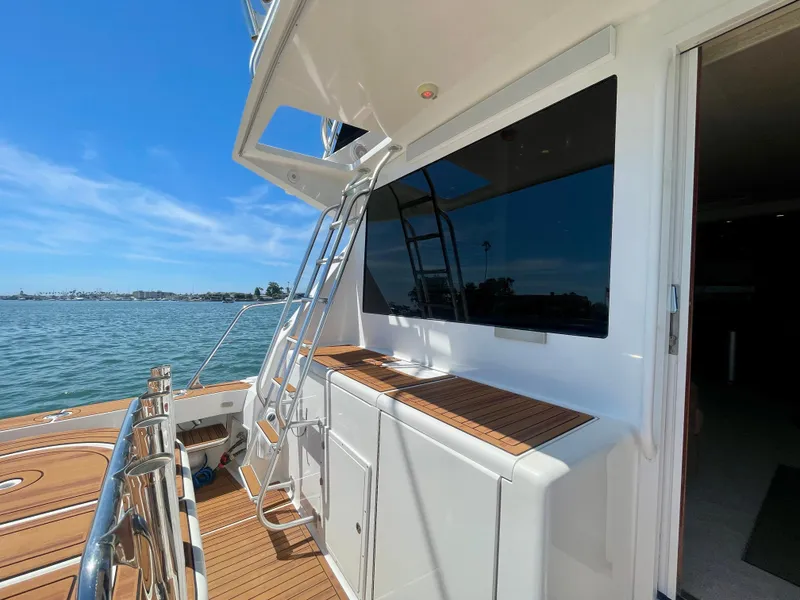 Slide: The Image of 1998 Viking 50 Convertible yacht deck with ladder, overlooking calm waters and clear sky. - 13