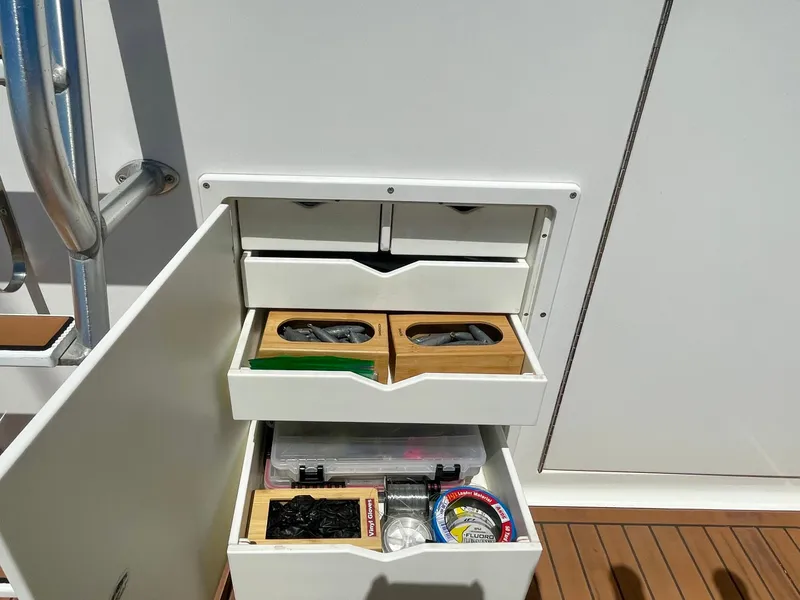 Slide: The Image of Open storage drawers on a 1998 Viking 50 Convertible boat, containing fishing gear and supplies. - 25