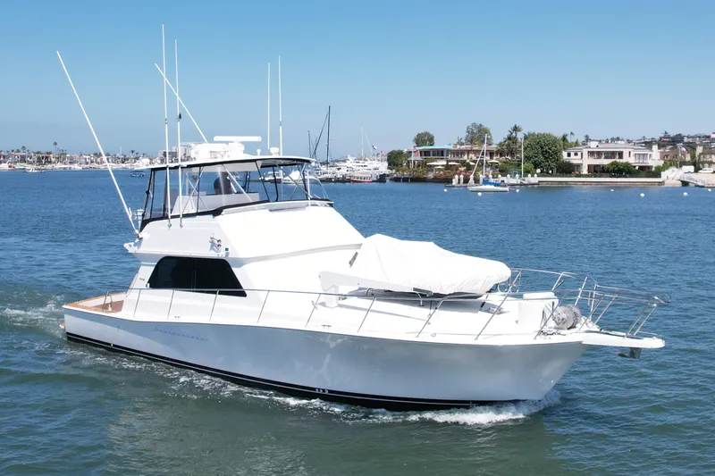 Slide: The Image of 1998 Viking 50 Convertible yacht cruising in a scenic harbor setting. - 3