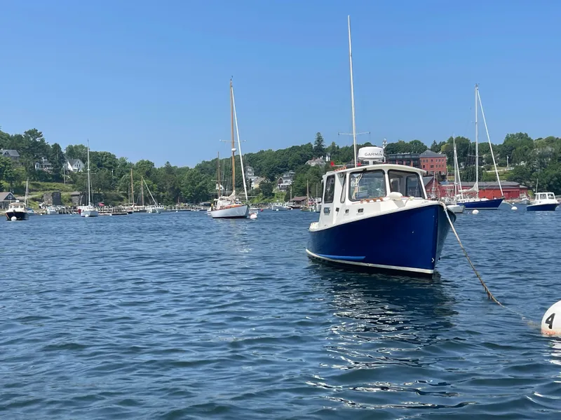 Slide: The Image of 2005 Atlas Boat Works Pompano 21 anchored in scenic harbor with sailboats and shoreline. - 13