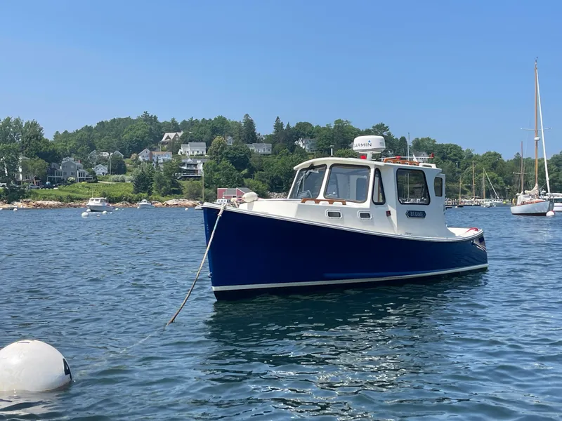 Slide: The Image of 2005 Atlas Boat Works Pompano 21 moored in scenic harbor with lush green backdrop. - 14