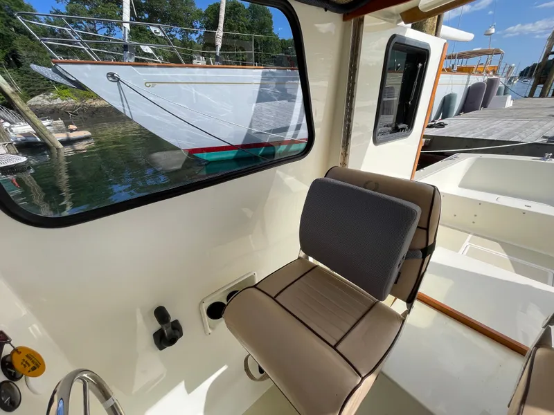 Slide: The Image of Interior of a 2003 Atlas Boat Works Pompano 21, featuring a cushioned seat and window view. - 41